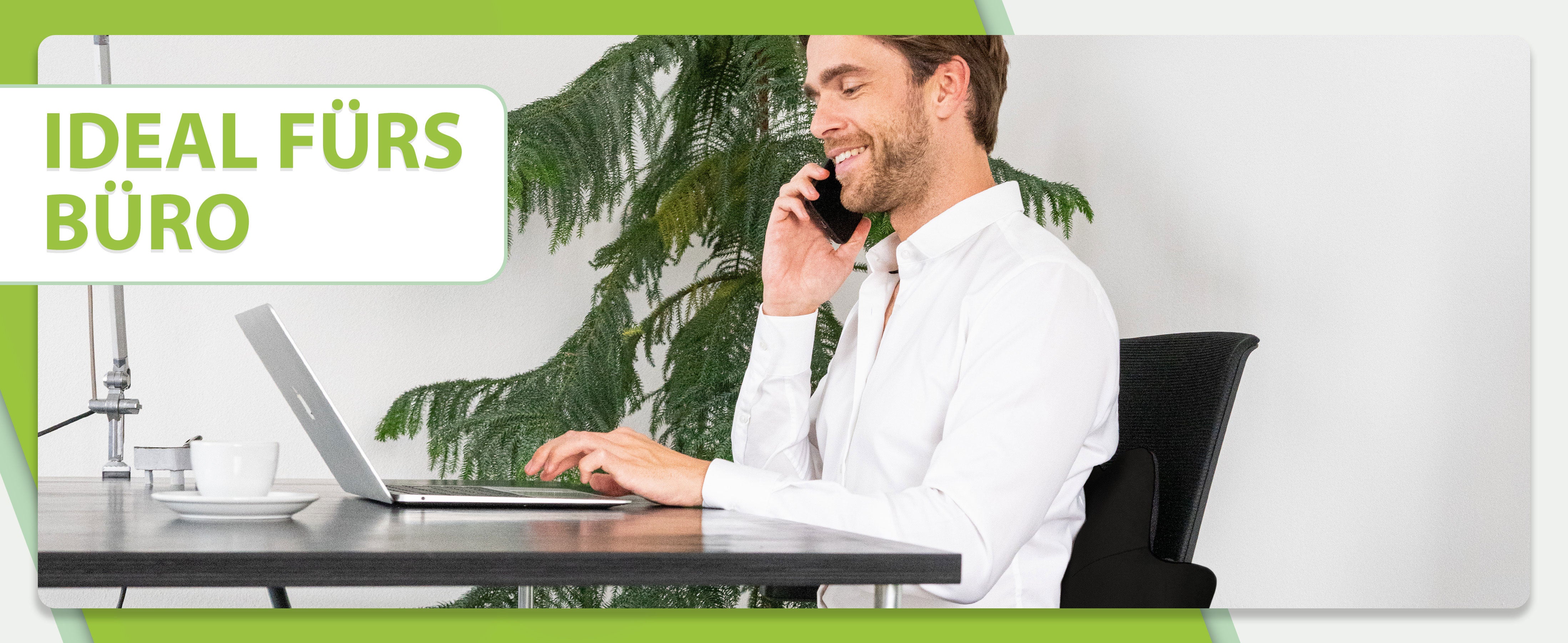 Ideal fürs Büro: Der Mann telefoniert und arbeitet an einem Laptop, sitzt auf einem Stuhl mit dem feela Rückenkissen in Schwarz für gesunde Haltung.